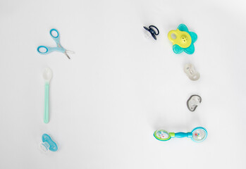 Baby care items on a white background: scissors, rattle, teethers, pacifiers, spoon