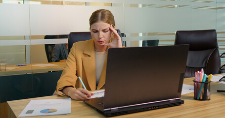 Caucasian businesswoman suffering from headache due to computer overwork. Workaholic people concept.