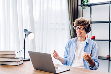 Obraz premium Young smiling man relaxing using laptop computer working and video conference meeting at home.Young creative man looking at screen typing message at home.work from home concept