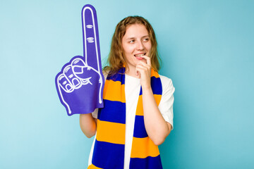 Young caucasian sports fan woman isolated on blue background relaxed thinking about something looking at a copy space.