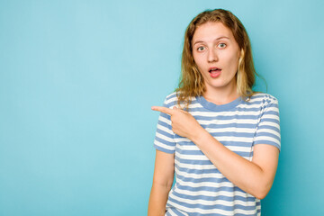 Young caucasian woman isolated on blue background pointing to the side