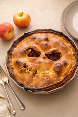 Halloween pie with funny pumpkin face carved on pie, top view. Autumn baking