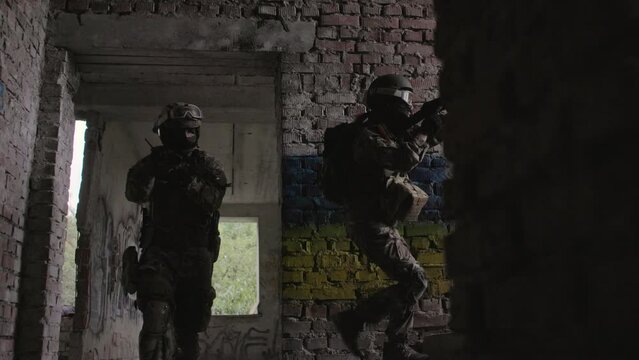 Ukrainian Soldiers military in the war with a weapon in his hands. The flag of Ukraine is painted on a brick wall. Relations between Ukraine and Russia
