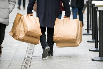 Person carrying many paper bags on a street