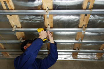 Man fasten metal profile frame to the ceiling for plasterboard installation