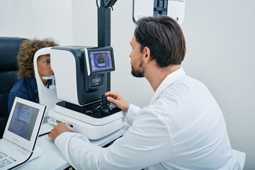 Optometrist using autorefractor determining required level of vision correction and determining individual's prescription for glasses for male child