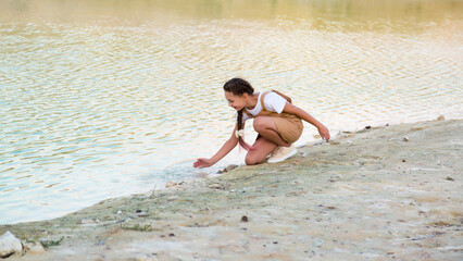 Teenage girl splashes water from the river and laughs.