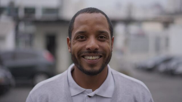 Happy African American young man looking at camera smiling. A Brazilian South American guy standing outdoors in urban street