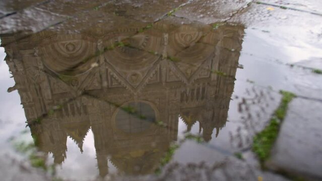 Panning view of imposing church reflects in puddle. Italy. Daylight. 