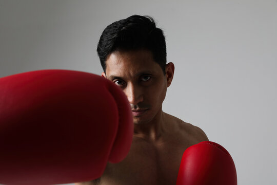 Close-up of attractive fitness angry asian man play boxing with gloves. Mock-up.