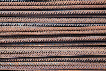 Pile of reinforcing steel bars, known also as rebars, used as construction material in reinforcing concrete or masonry work, close-up of the rusty rods with spiral ridges forming symmetrical patterns