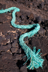 Old plastic rope with frayed ends and deteriorated fibers coming out washed ashore, synthetic materials used on ships and boats lost in the ocean polluting the environment and affecting the wildlife