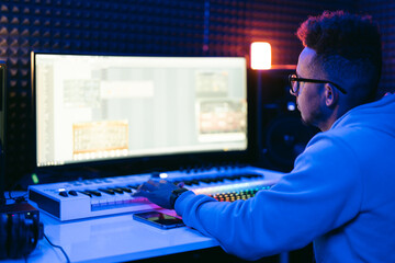 Producer, audio engineer uses a control panel and screen to record a track of a new album in a recording studio, in a soundproof room. Image producer, designer in working process