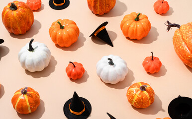pattern of colorful artificial pumpkins and halloween hats on orange background