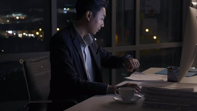 Stressed young Asian businessman working overtime at the office.