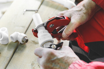 Tool for cutting plastic pipes in the hand of an adult man close-up.Plumber cutting plastic pipe.