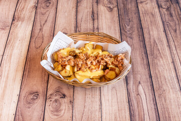 Roasted potato basket with fried chicken, bacon and sauces on wooden table