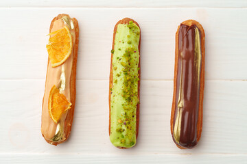 Beautiful french eclairs set on white wooden background