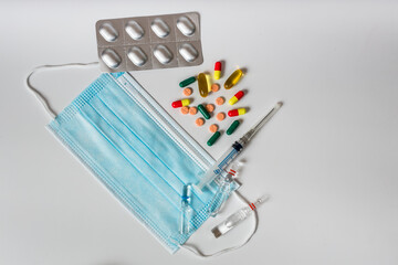 Pills, syringe and thermometer for treatment lie on a white background
