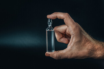 Medical bottle in hand on a black background. Flat lay arrangement with Pharmaceutical industry concept. Pharmacy drugstore. Antibiotic drug resistance. 