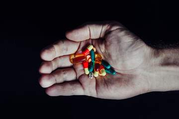 Mountain of pills in the hand of a doctor on an isolated black background
