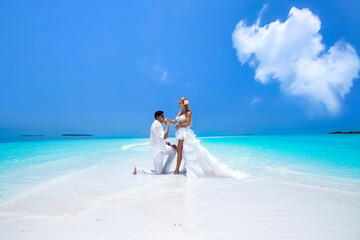 Summer love. Beautiful happy young couple in wedding clothes is standing on a beach in the...