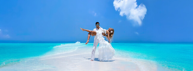 Summer love. Beautiful happy young couple in wedding clothes is standing on a beach in the...
