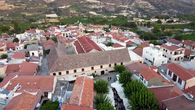 Aerial drone footage of traditional countryside village Omodos, Limassol, Cyprus. 360 orbit view of Timios Stavros (Holy Cross) monastery, tiled roof houses and balconies, narrow streets from above.