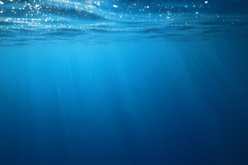 Obraz premium ocean underwater rays of light background, under blue water sunlight