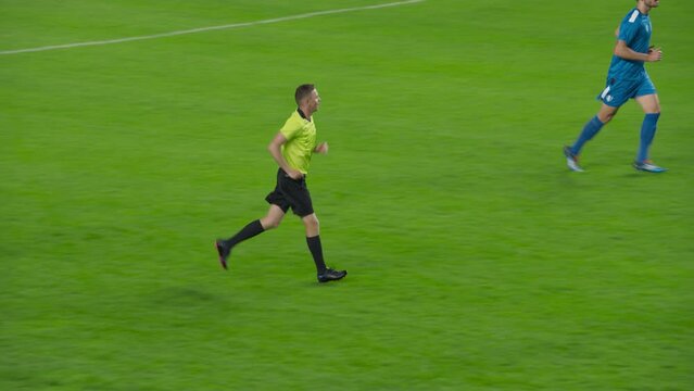 Professional Soccer Football Match Championship: Referee Running on the Field, Raising Arm, Showing Sign of Indirect Free Kick, Offside, Corner Kick. Live Sport Broadcast Channel Television Playback