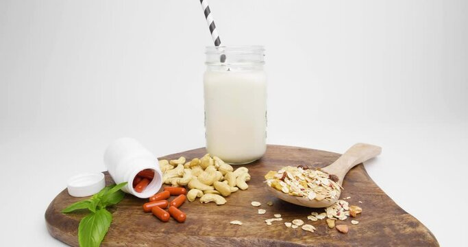 cutting board with cashews and pills with cereals for a beautiful breakfast against white background