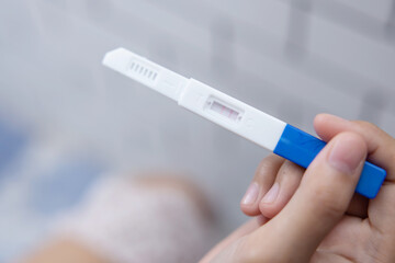 Fototapeta premium Female Hand Holding Positive Pregnancy Test on the Toilet
