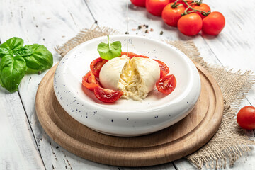 fresh soft white burrata cheese ball made from mozzarella and cream from Apulia, Italian Mediterranean cuisine, Food recipe background. Close up