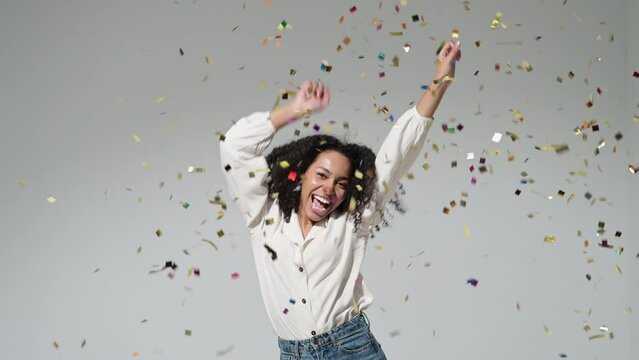 Happy woman at celebration party with confetti falling everywhere on her, Beautiful girl dancing, having fun and enjoying life. Birthday, Christmas, New Year eve celebration concept