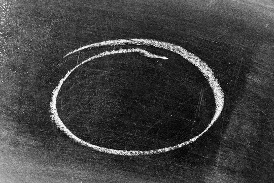 White chalk hand drawing as circle or round shape on blackboard or chalkboard background with copy space