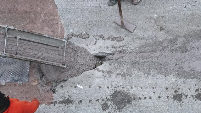 Worker Shoveling Fresh Cement pre-mixed concrete in the track, which drips from the hopper of a mixer truck