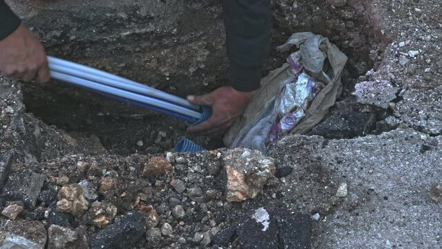 Worker slips fiber optic cables into underground corrugated pipe
