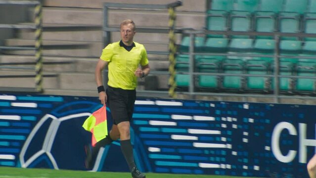Soccer Football Match Championship: Referee Running on the Field with a Signal Flag. Live Sport Broadcast Channel Television Playback. Slow Motion Tracking Shot