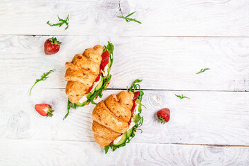 croissant sandwich with strawberries, arugula, avocado and brie, camembert cheese. banner menu recipe place for text, top view.
