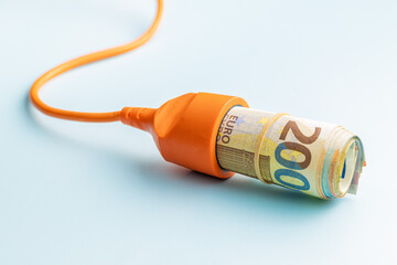 Electric socket and euro money on blue background. Concept of increasing electric prices.