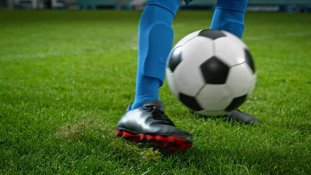 Close-up of a Leg in a Boot Kicking Football Ball. Professional Soccer Player Hits Ball with Fierce Power, Scores Goal, Grass Flying. Super Slow Motion Cinematic Low Angle Ground Artistic Shot