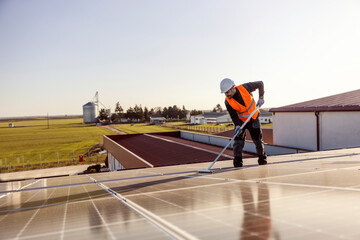 A tidy worker is cleaning solar panels on the roof.