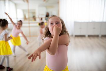 Little girl with down syndrome imitating elephant, having fun during ballet leson at dancing school.