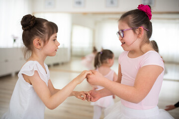 Little disabled girls dancing together in ballet school studio. Concept od integration and education disabled children.