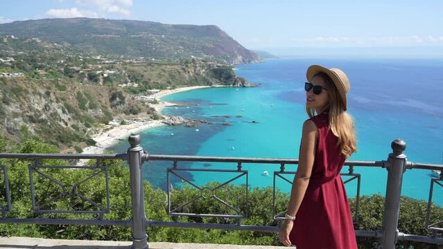 Vacation in Calabria, Italy. Smiling beautiful fashion girl enjoying view of Capo Vaticano beach in Calabria, Italy. Summer vacation in southern Europe.