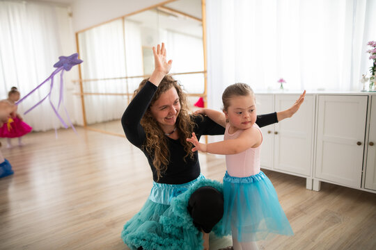 Little girl with down syndrome learning ballet with dance lecteur in ballet studio.