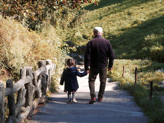 Un grand père et une fillette se baladent dans un parc, style photo ancienne