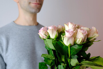 close-up of bouquet of white, pink roses in hands of young man, brought flowers on date with girlfriend, gives to mom, concept of mother's, Valentine's day, birthday, declaration of love