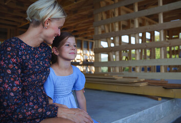 Mother and daughter on site inside new ecology wooden home construction framing.