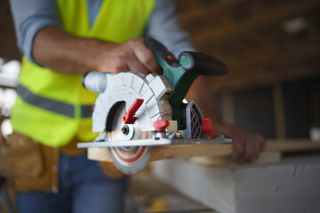 Close-up of construction worker working with eletric saw inside wooden construction of house, diy eco-friendly homes concept.